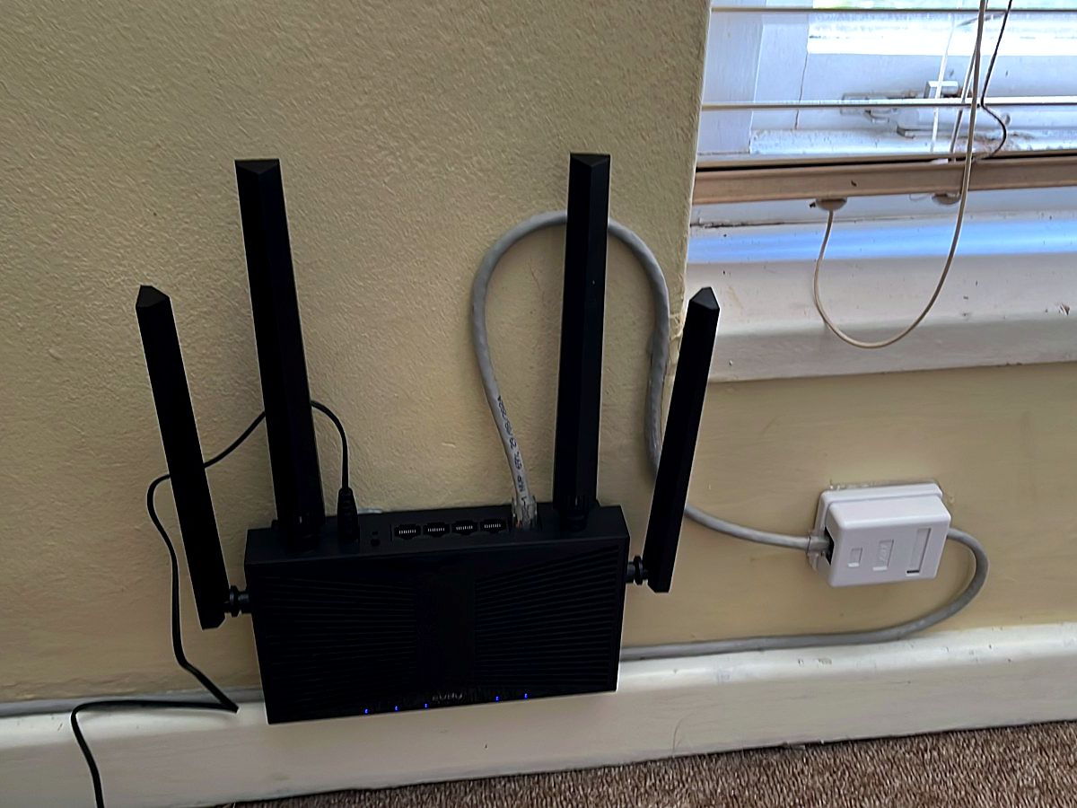Black 4G LTE router with four antennas mounted on a wall beside a data point